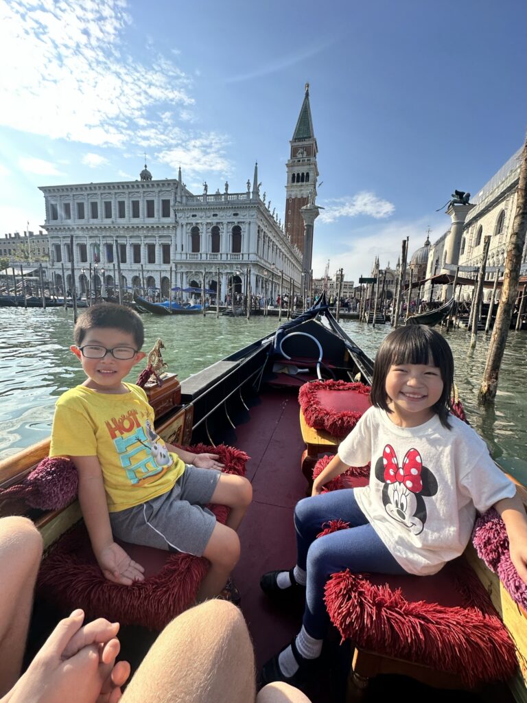 kids on a gondola ride in venice italy on family trip