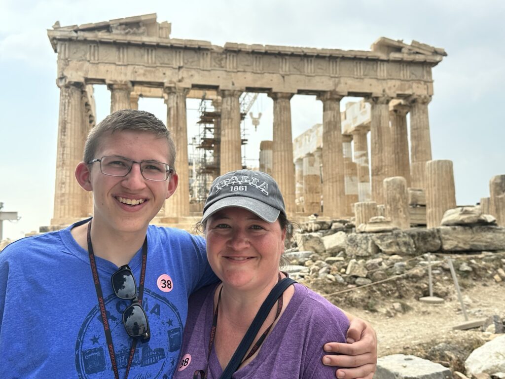 mother and son visiting parthenon in athens greece with greek ruins behind