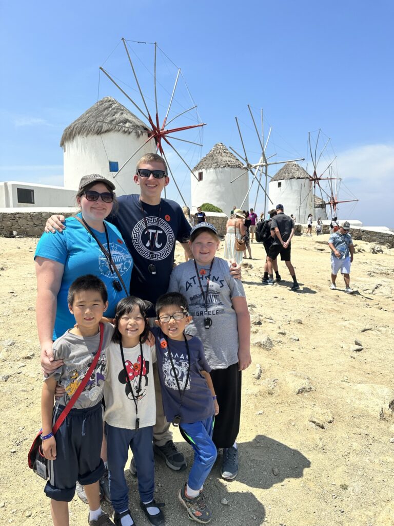 family of 8 with windmills behind in mykonos greece