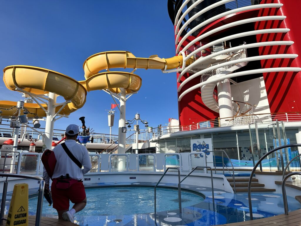 disney magic cruise pool area with yellow slide and kids pool with gyro place and aqua lab behind it