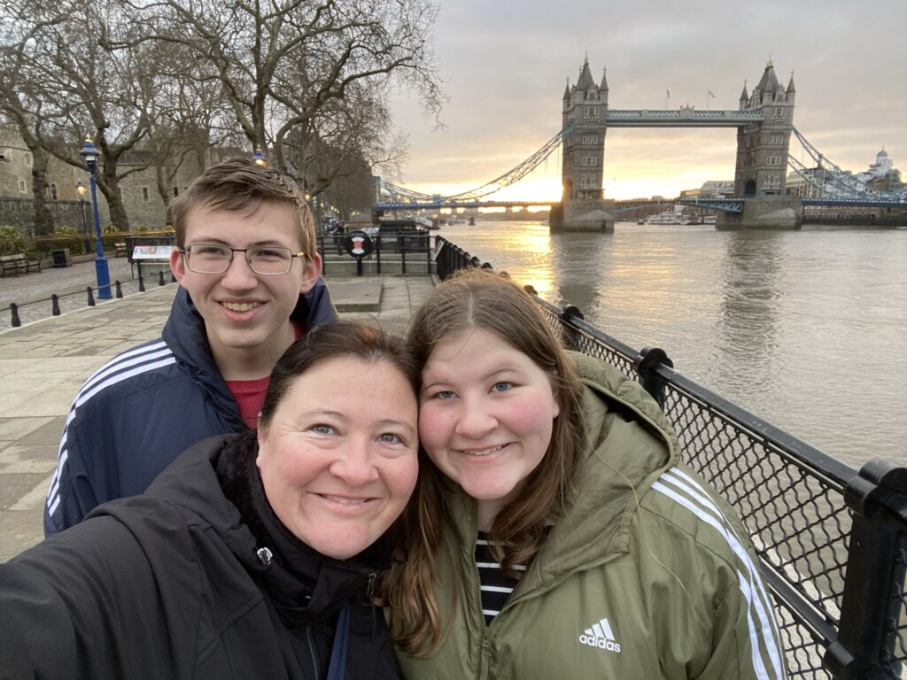 mother and oldest two kids in london england with picturesque tower bridge behind at sunrise