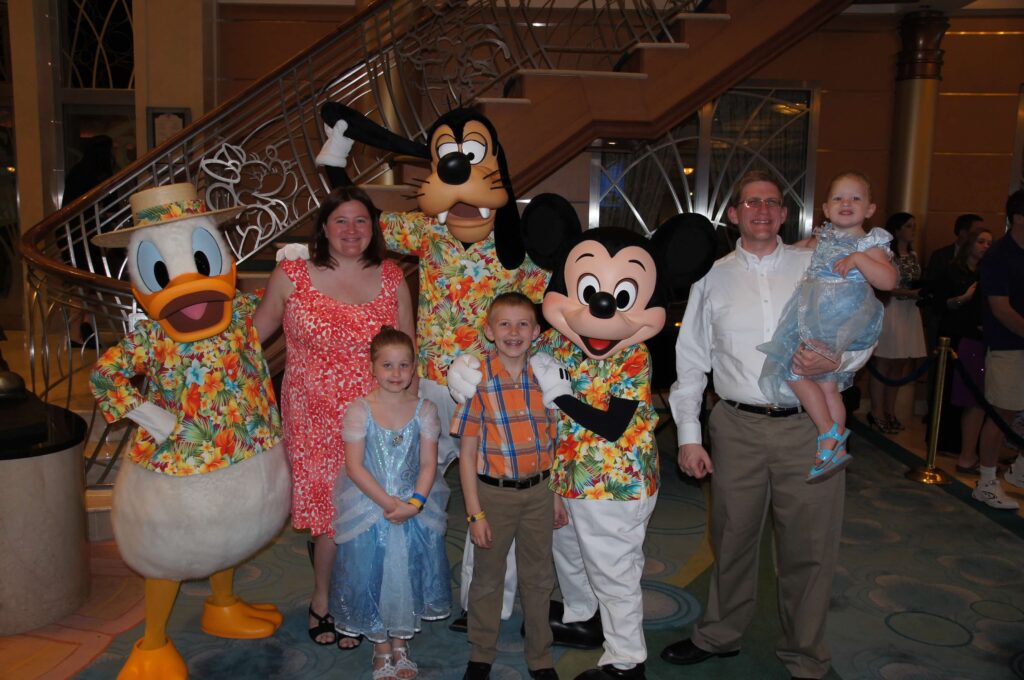 family picture with donald, goofy, and mickey on disney magic transatlantic cruise all in beach attire