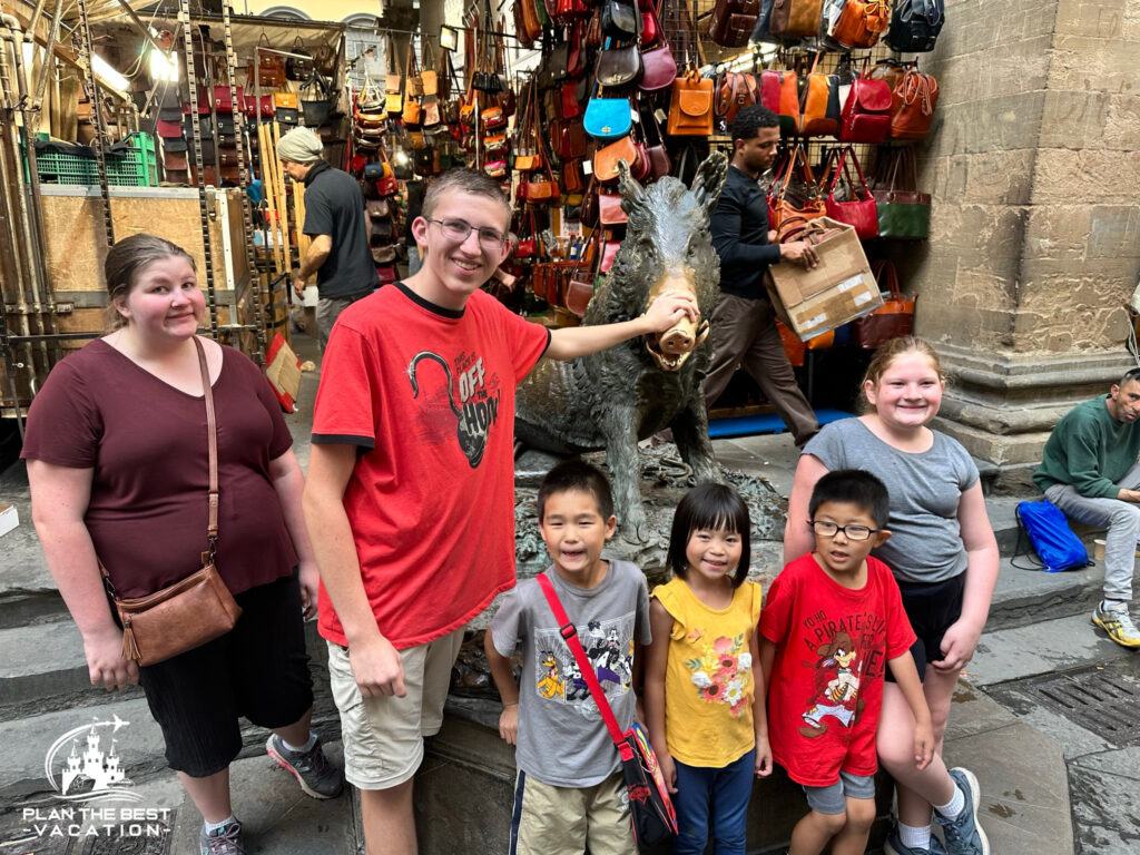 kids rubbing Fontana del Porcellino (pig statue) snout in florence italy