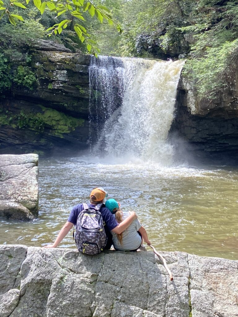 father and daughter relaxing looking at waterfall after hike