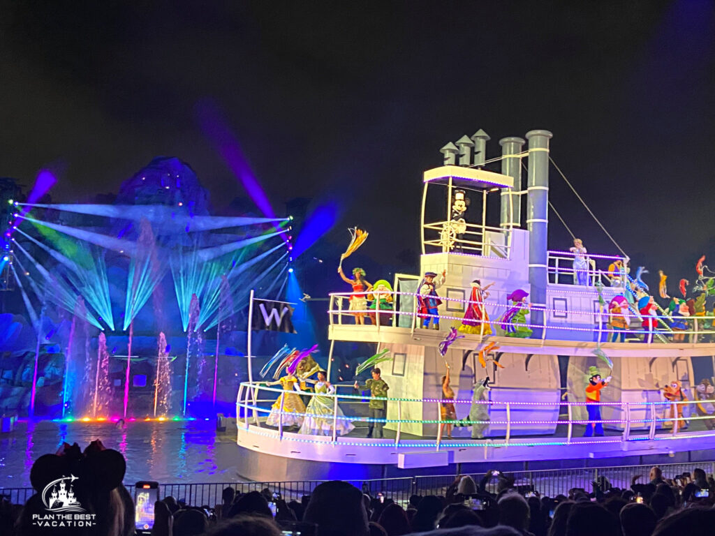 disney fantasmic show at disneyland and disney world with steamboat willie drivint the boat filled with disney favorite characters with mountain and colorful water behind