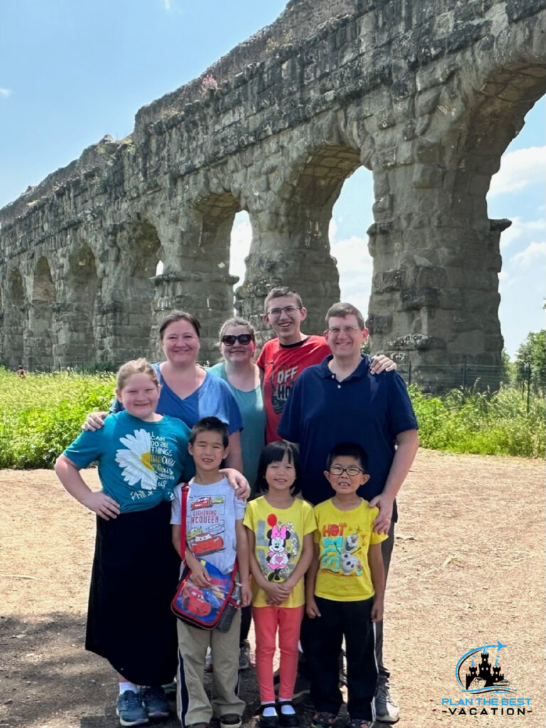 family in front of roman aqueduct on vacation in rome italy