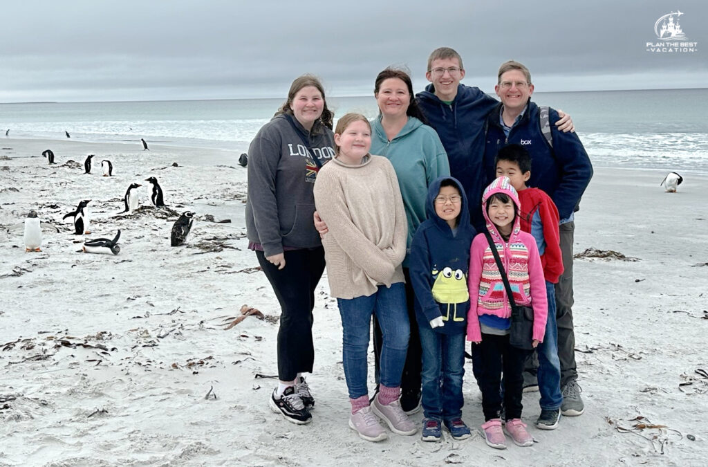 family with gentoo penguins at berthas beach in falkland islands