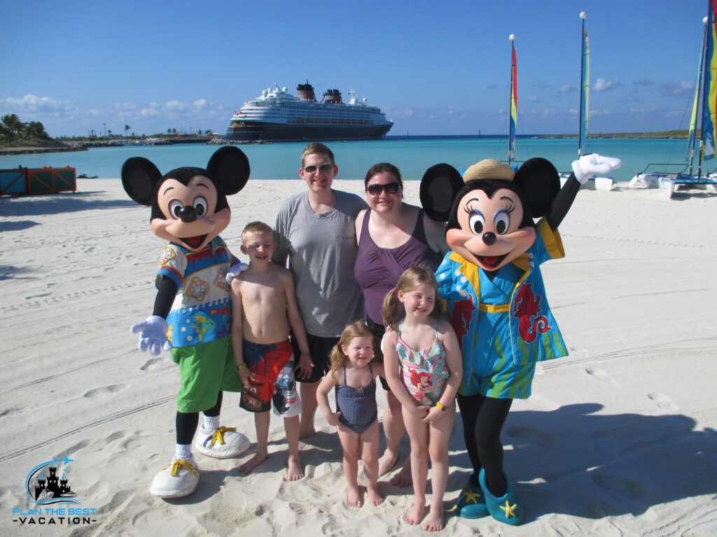 family with mickey and minnie on castaway cay beach with disney cruise ship behind them