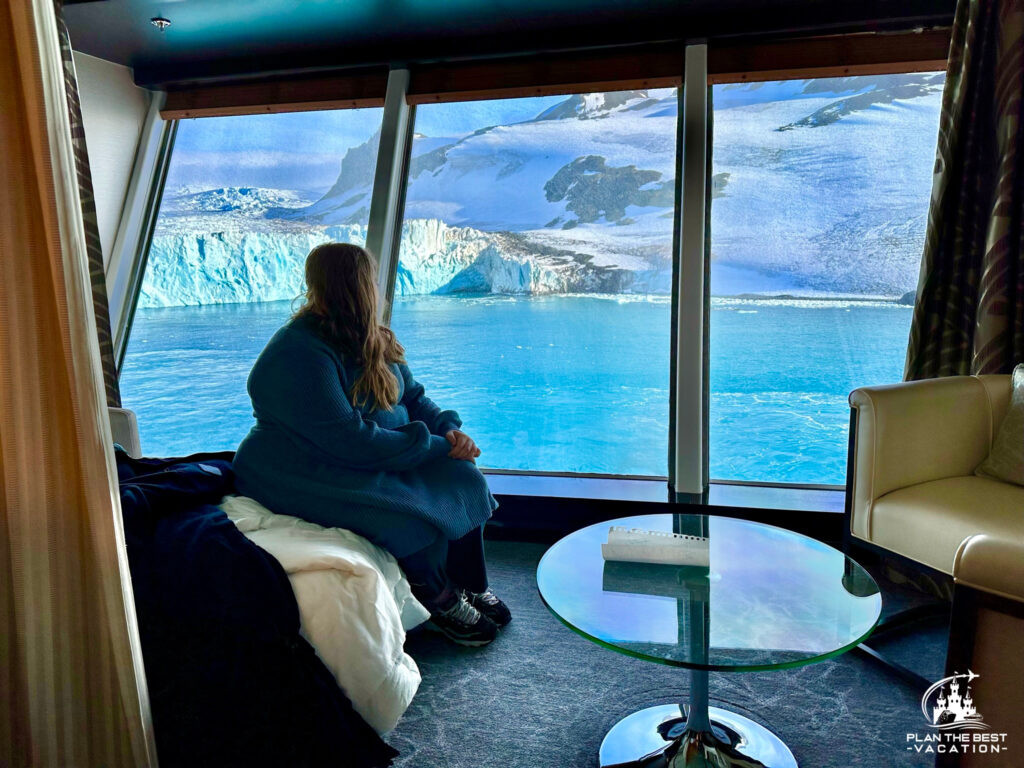 girl enjoying the stunning snowy view of Antarctica from inside major cruise ship large window