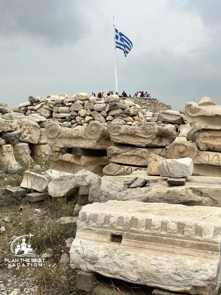 greek ruins on the acropolis with greek blue and white striped flag flying over top