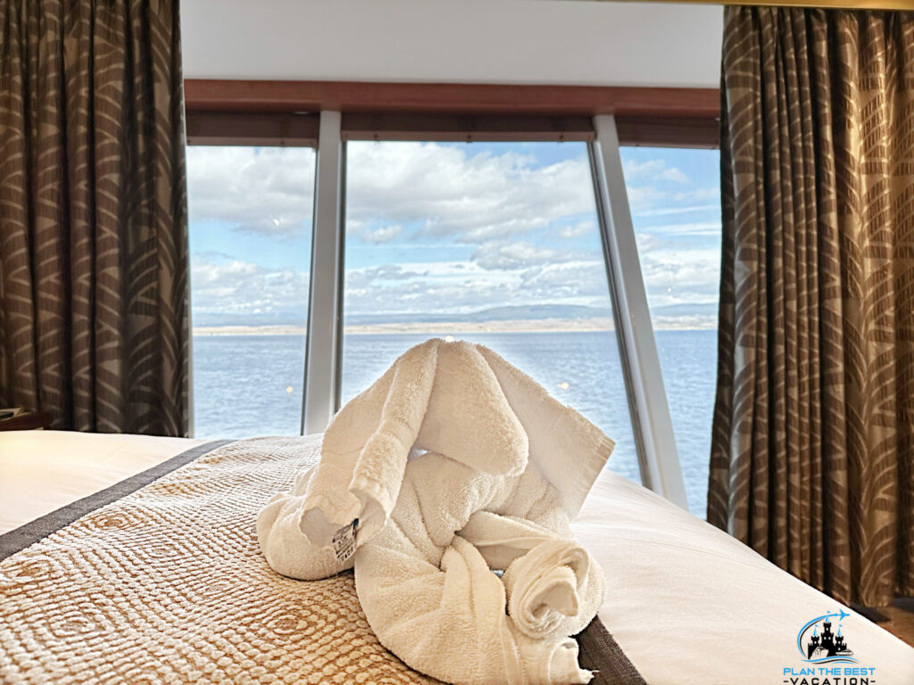 norweigan star bed with elephant towel animal with coast and beautiful clouds in the window behind