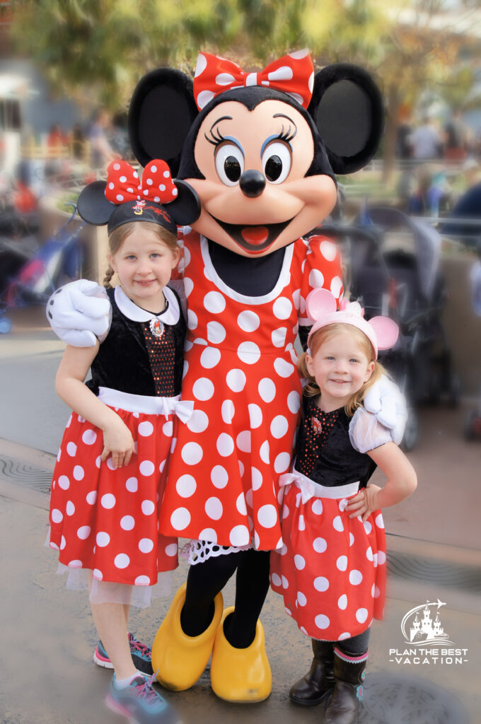sisters with minnie mouse in matching minnie dresses at disneyland california