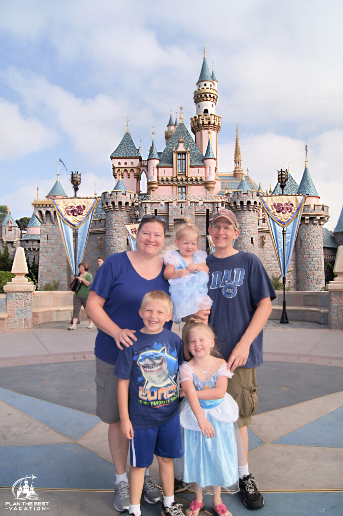 young family in front of disneyland sleeping beauty castle in annaheim california